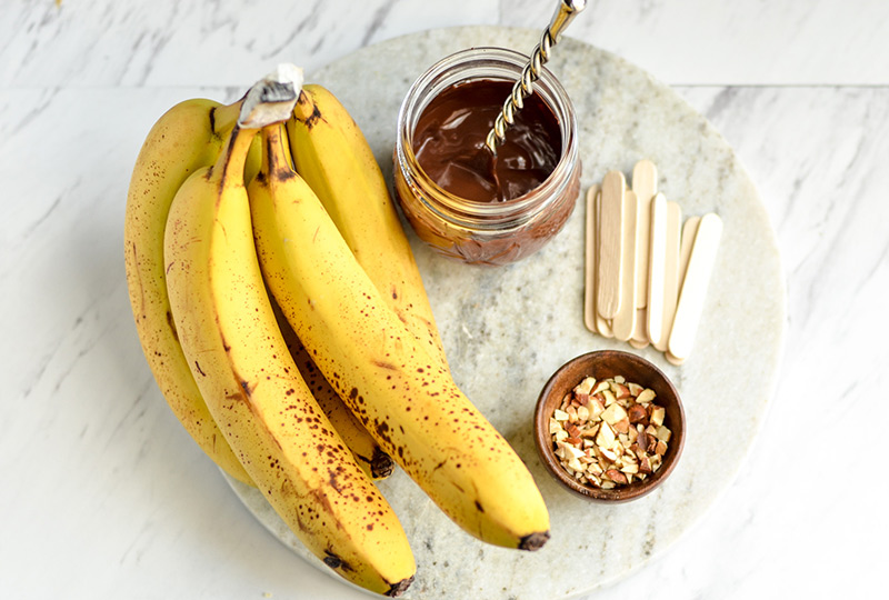 Bananas, melted chocolate, nuts and popsicle sticks