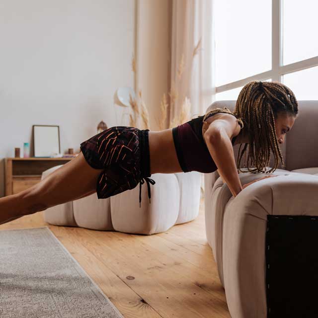 Woman doing workouts without equipment in her living room.