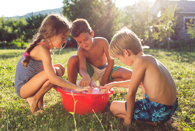 three kids playing with a bucket of water