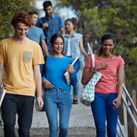 A group of teens walks down a set of stairs outside a school.