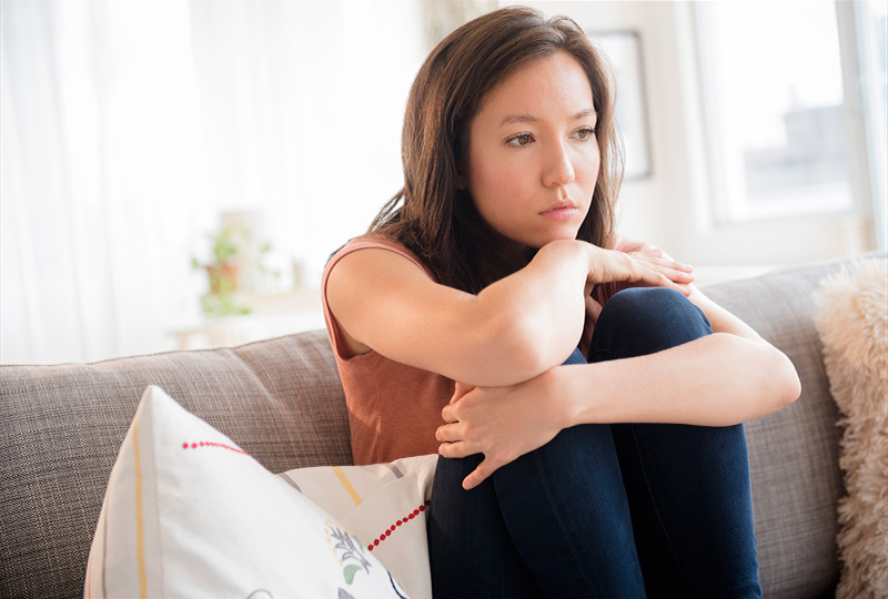 Woman sitting on couch looking tense