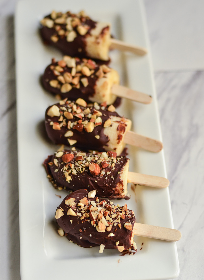 Frozen chocolate-dipped bananas lined up on platter.