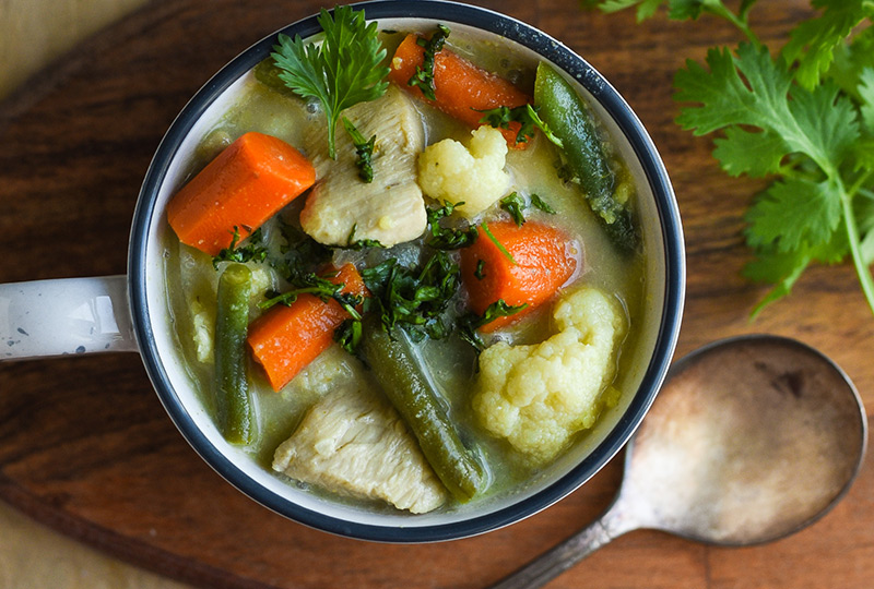 Closeup photo of chicken and vegetable Thai soup in a bowl.