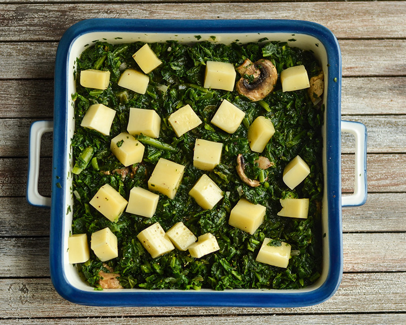Diced cheese, spinach and mushrooms in baking pan