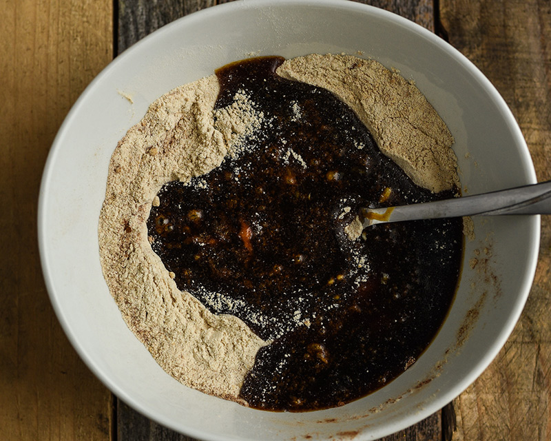 Mixing bowl containing flour with molasses mixture poured on top.