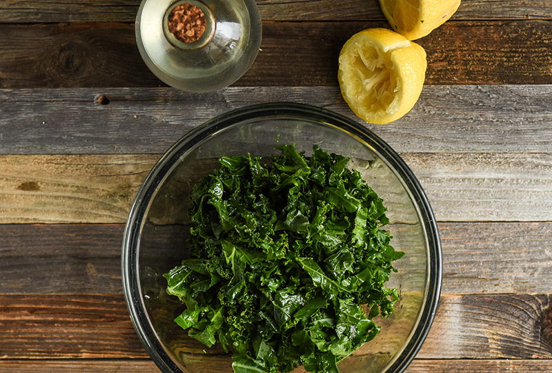 Kale in a mixing bowl with freshly squeezed lemon juice