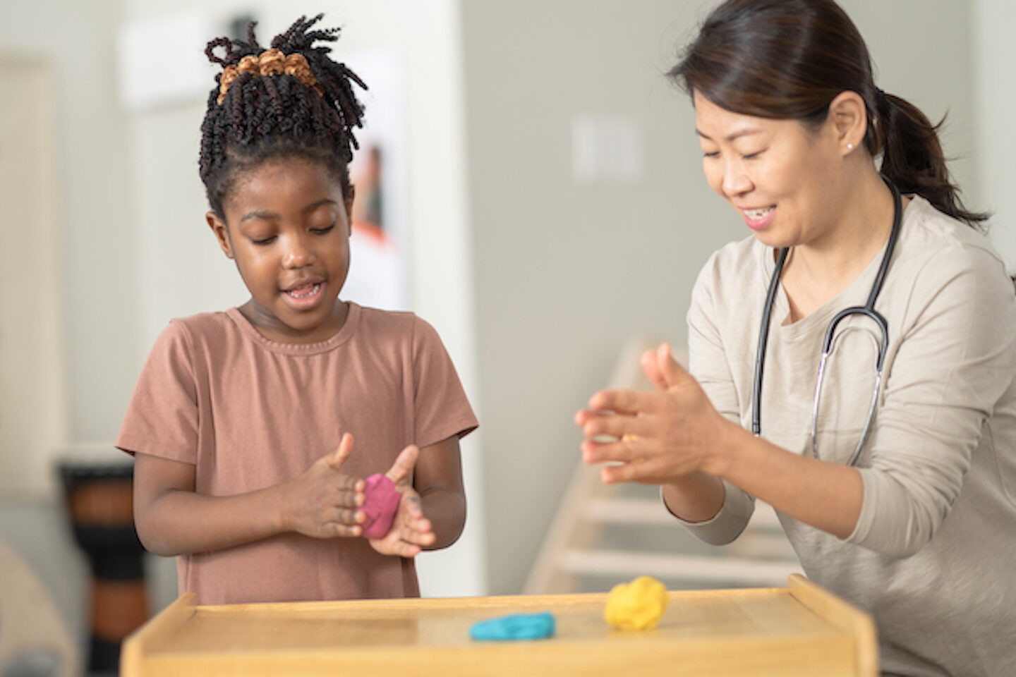 Female doctor playing with play dough with a young girl