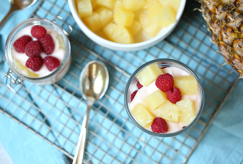 Bowl of pineapple chunks and two glasses of pineapple-raspberry parfaits.