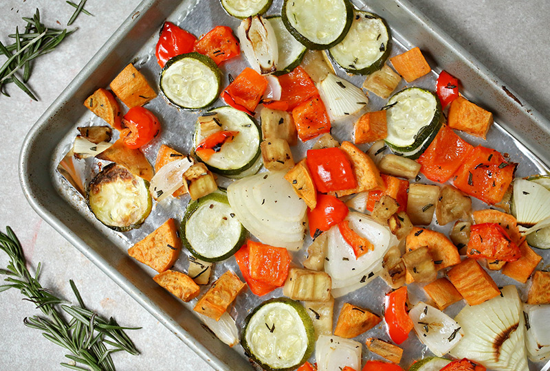 Roasted zucchini, sweet potato, eggplant and peppers on a baking pan.