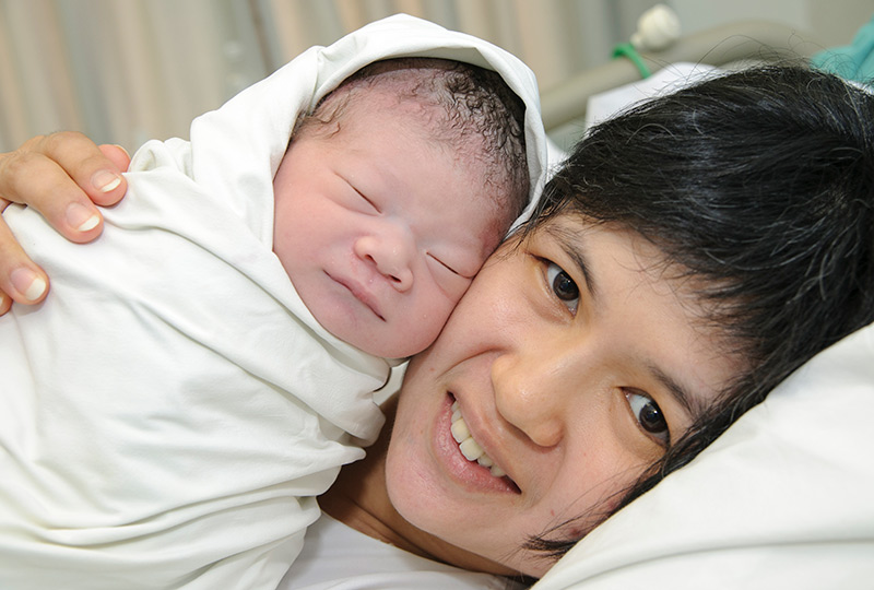 A woman snuggles with her newborn baby.