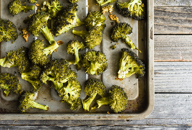 Roasted broccoli florets on baking pan.