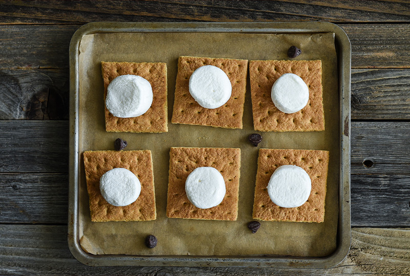 Graham crackers on a baking pan topped with marshmallows