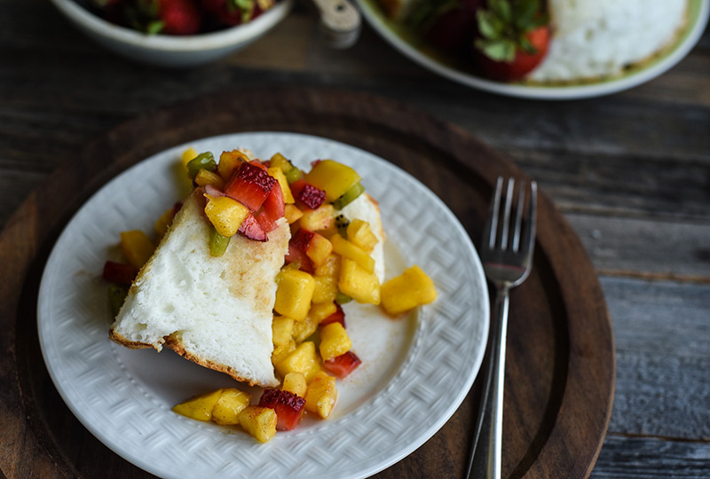 Angel food cake slice with fruit salsa spooned over it.