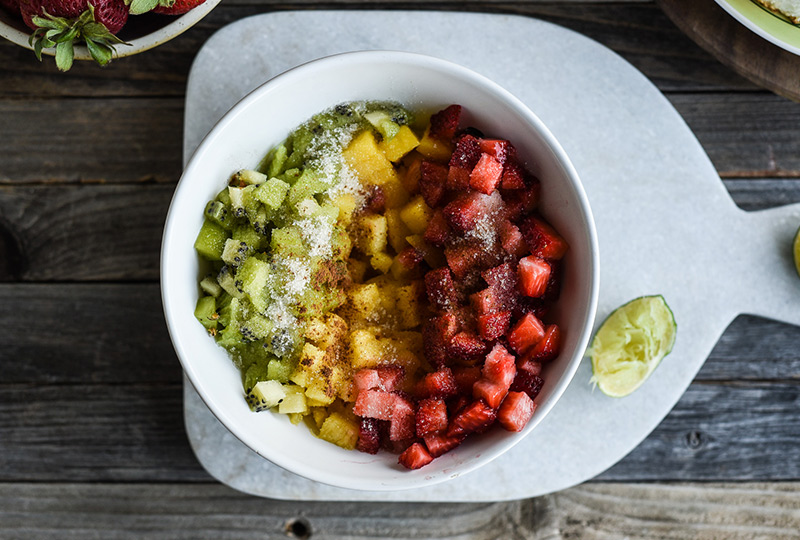 Strawberries, pineapple and kiwi mixed in a bowl with cinnamon sugar