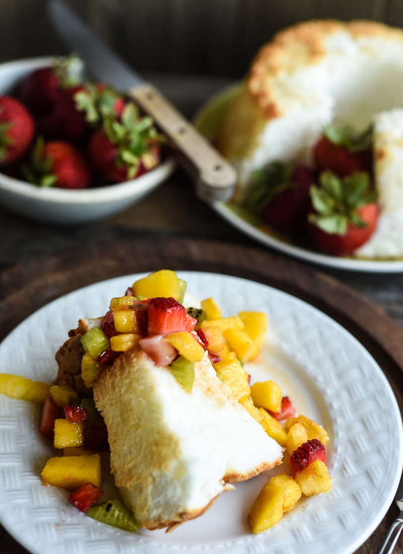 Angel food cake slice with fruit salsa spooned over it.