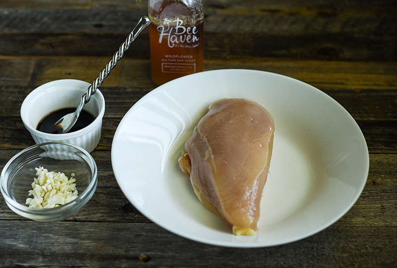 Raw boneless skinless chicken breast with honey and raw garlic ready to marinate. 