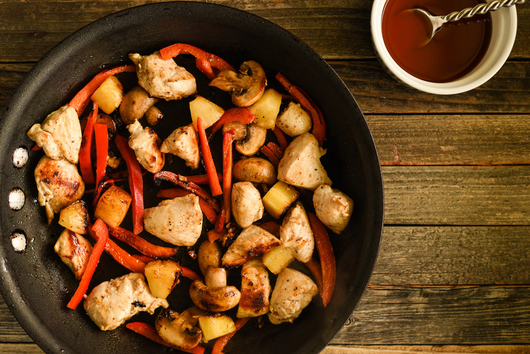Chopped chicken, pepper, mushroom and pineapple, stir-fried in a skillet