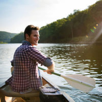 Man paddles a canoe on a lake