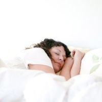Woman asleep in a bed with puffy white comforter