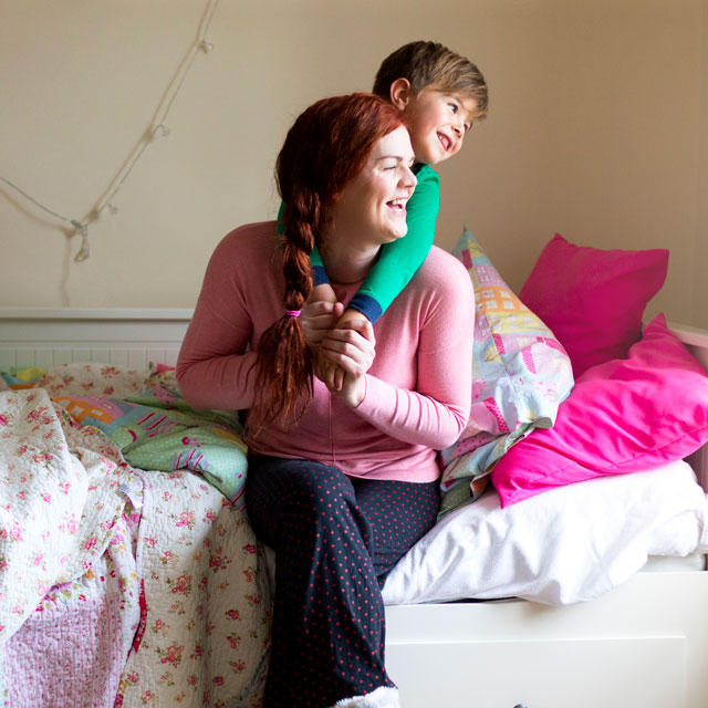 Mother playing with young son in pink bedroom