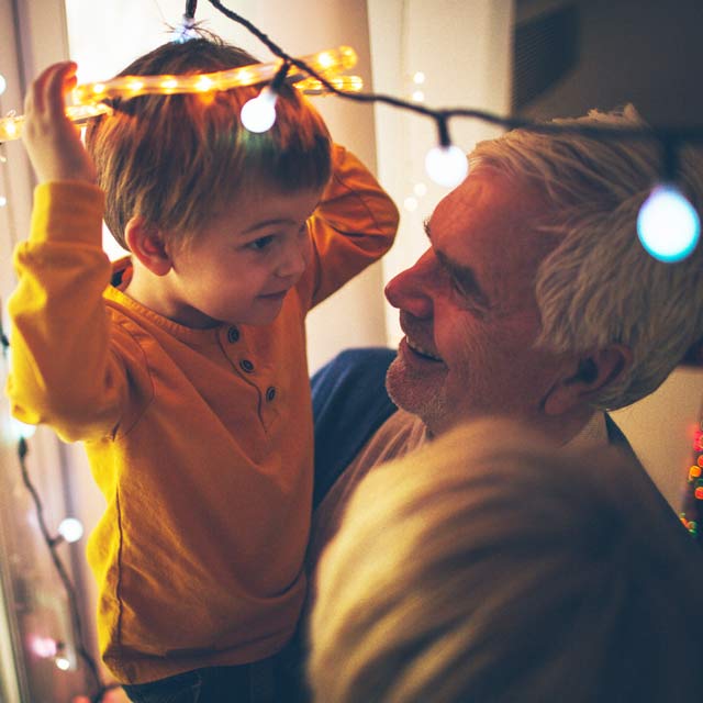 Grandpa spending time decorating for holidays with grandson