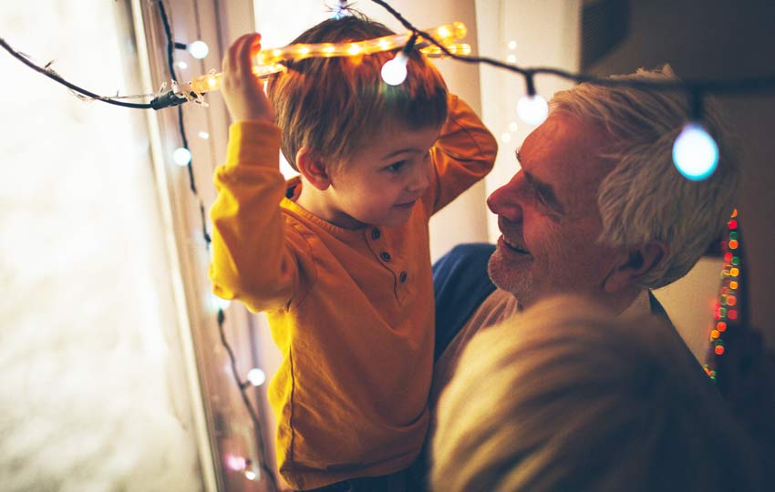 Grandpa spending time decorating for holidays with grandson