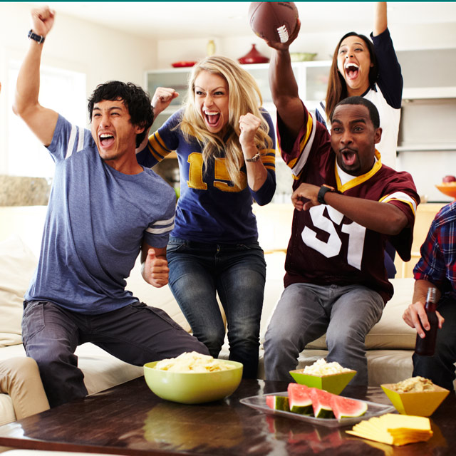 Group of friends in a living room getting excited about a football game on TV