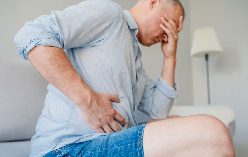 Man suffering from fatty liver disease and clutching stomach.