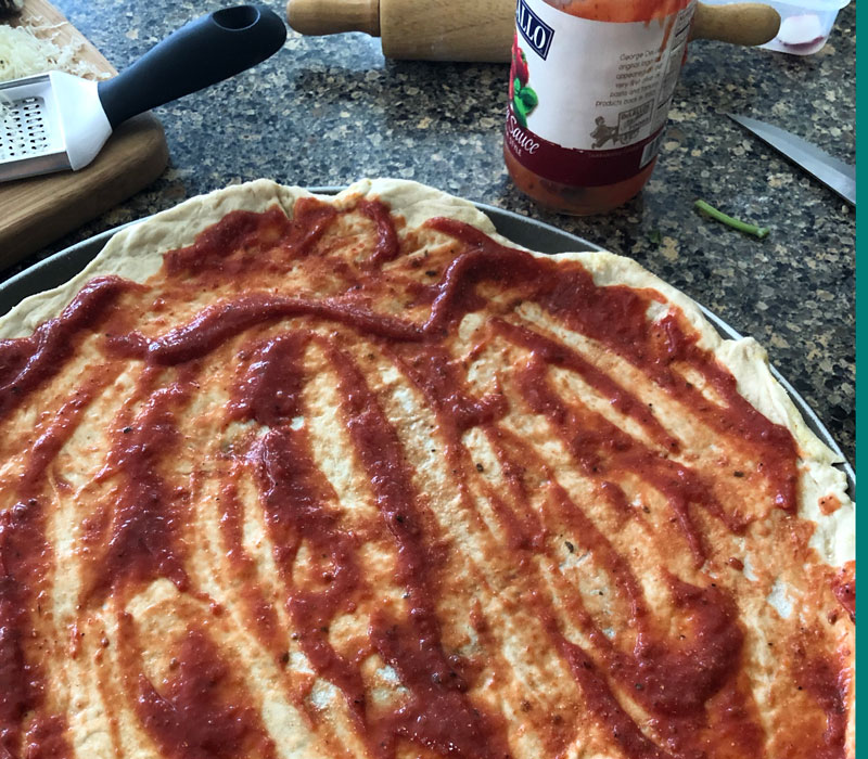 Tomato sauce spread over raw pizza dough.