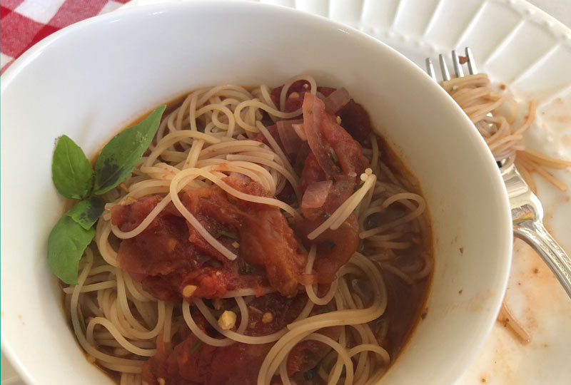 Homemade marinara sauce tossed in a bowl of spaghetti.