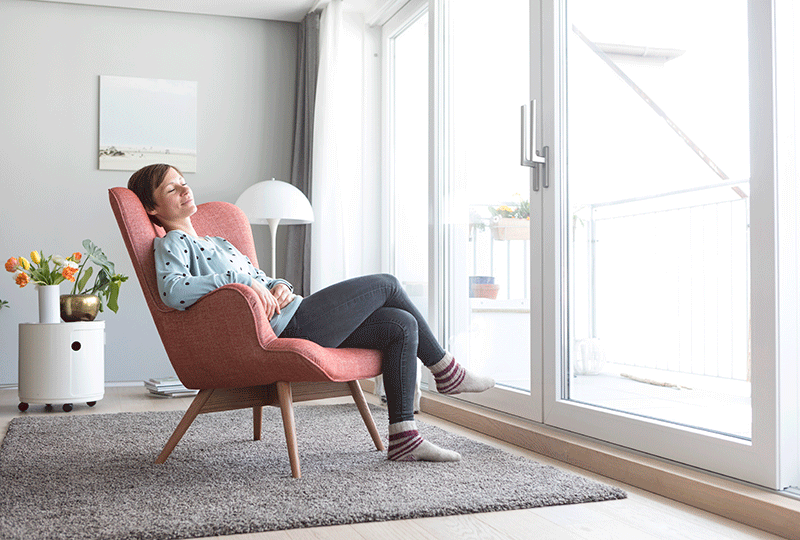 Woman relaxes in an armchair near a sliding glass door.