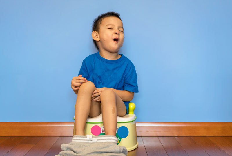 Young boy sitting on portable as he goes through potty training.