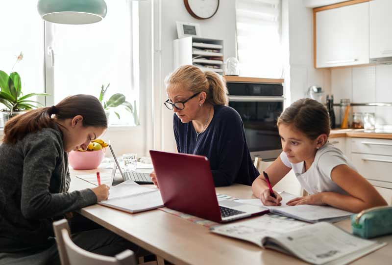 Mother working and children doing schoolwork while maintaining healthy relationship as a family.