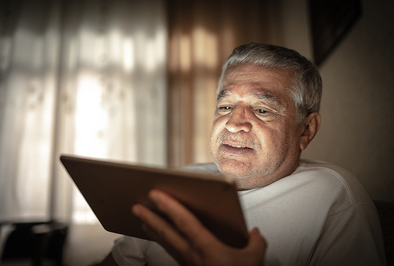 Emotional senior man doing a video call using a digital tablet at home
