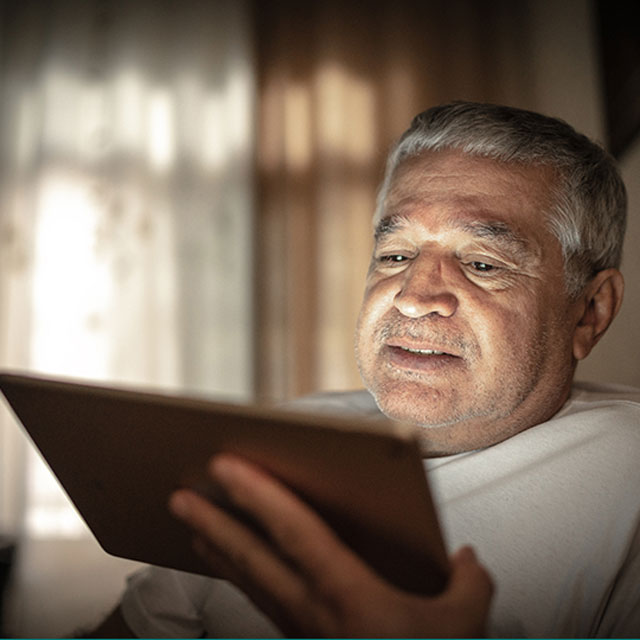 Emotional senior man doing a video call using a digital tablet at home