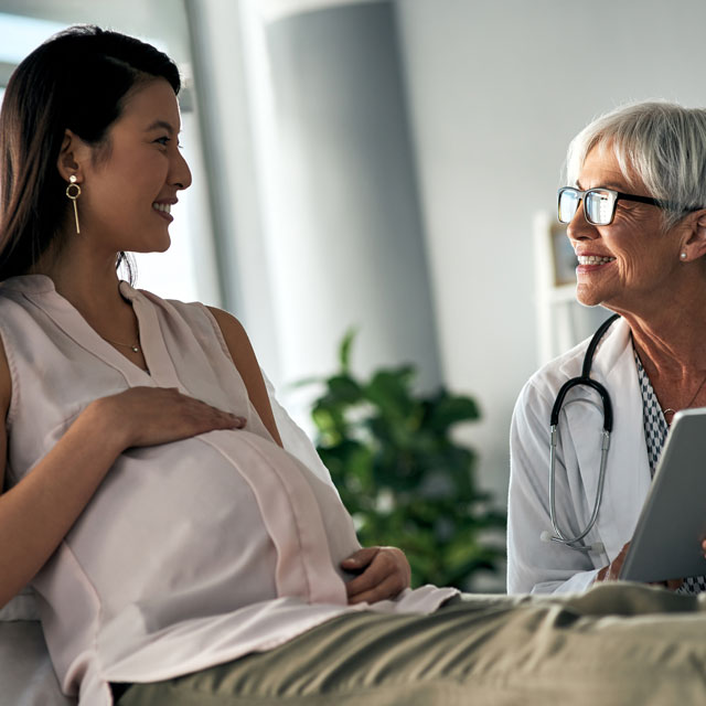 Pregnant Asian woman visits with a maternal-fetal medicine specialist.