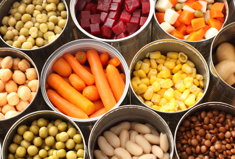 High-angle photo of variety of canned vegetables, with cans open to display the food.