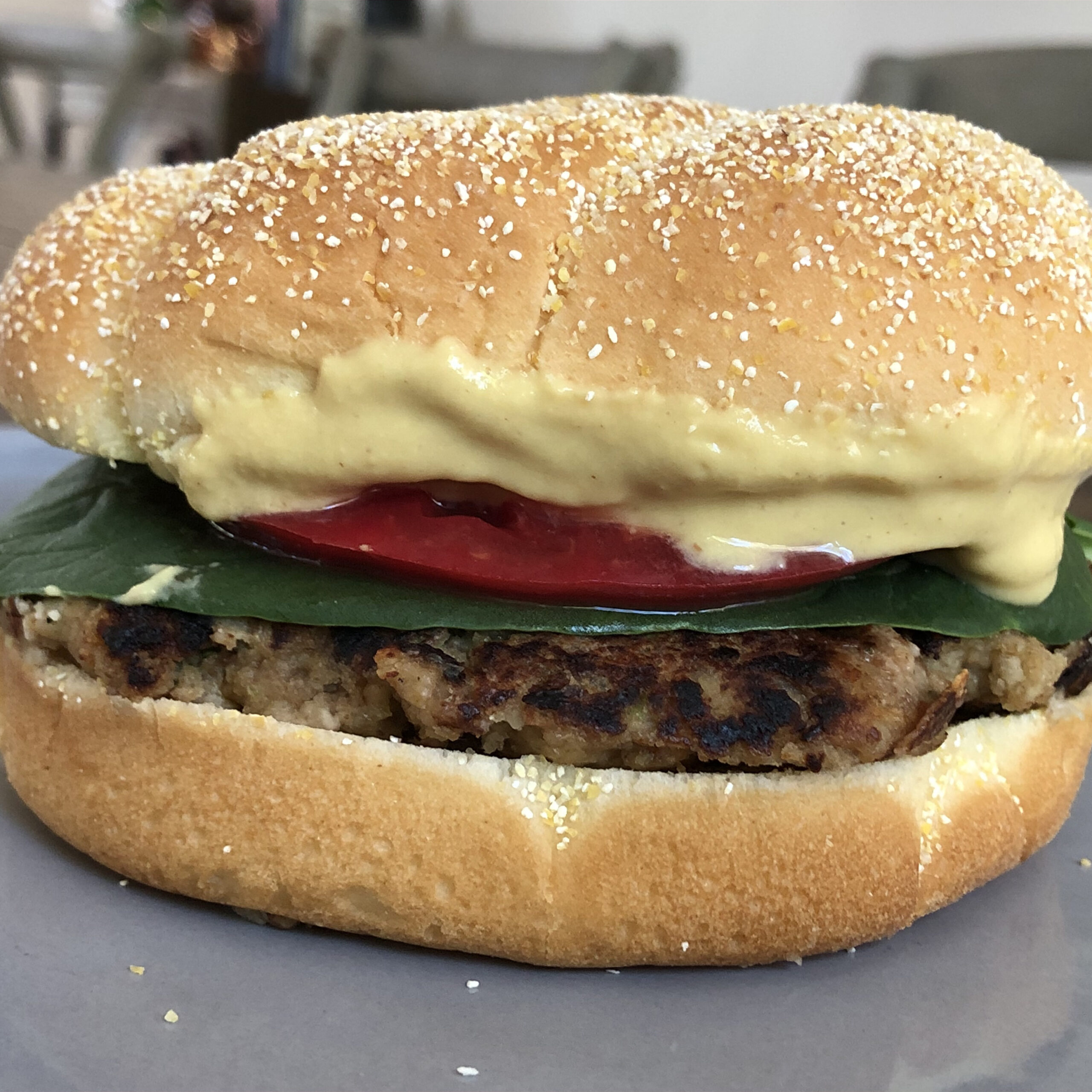 Closeup of a homemade veggie burger on a bun with cheese, tomato and spinach.