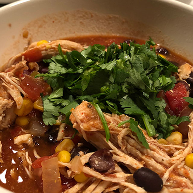 Closeup of a bowl of chicken tortilla soup with fresh cilantro topping.