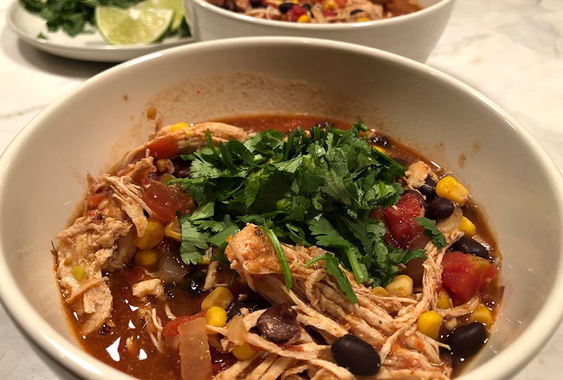 Closeup of a bowl of chicken tortilla soup with fresh cilantro topping.