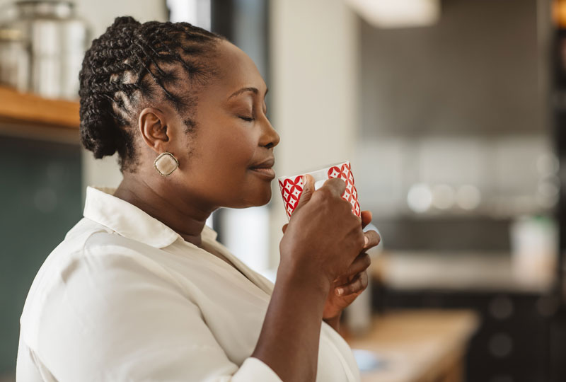 African-American woman savors the smell of a cup of hot tea.