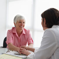 Thumbnail photo, older woman facing camera, talking with a younger doctor about vaginal and cervical cancer treatment options.