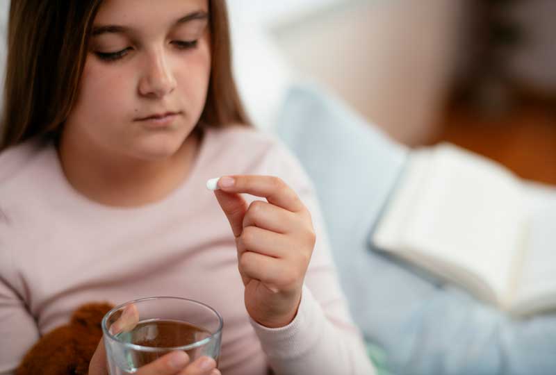 Child holding glass of water, taking antidepressant medication