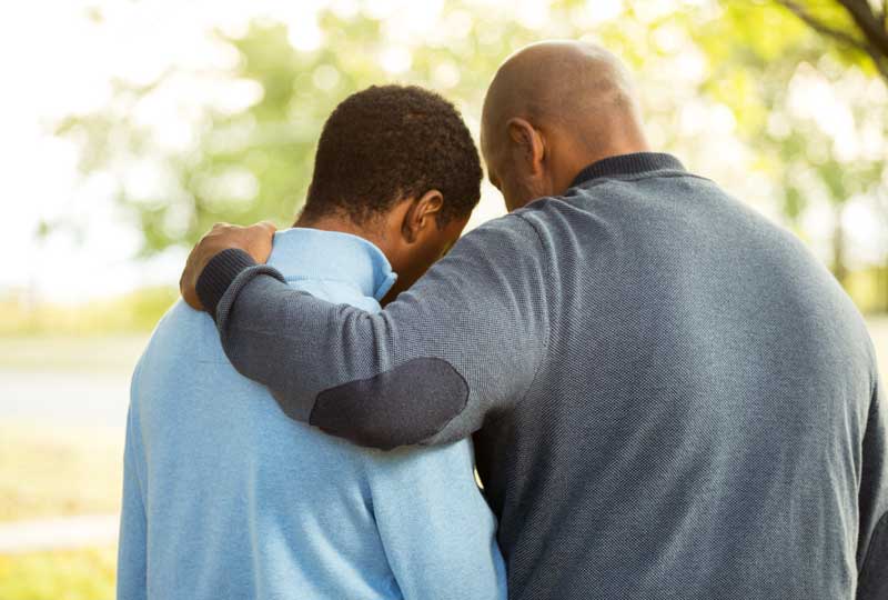 Parent embracing teen, speaking with child about mental health