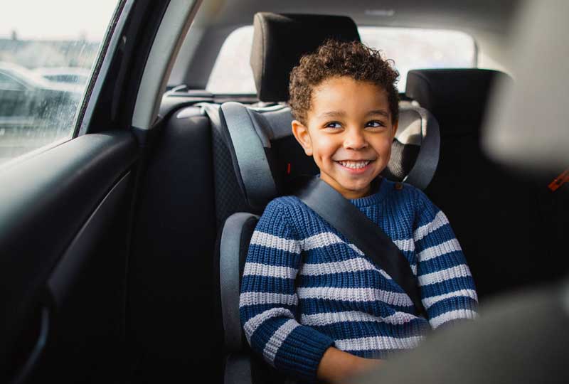 Child sitting in properly fitted car seat to prevent back injury in kids