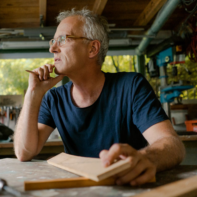 A middle aged man sits in his workshop.