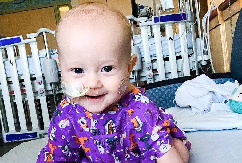 Baby recovering from RSV wearing a feeding tube in a hospital room