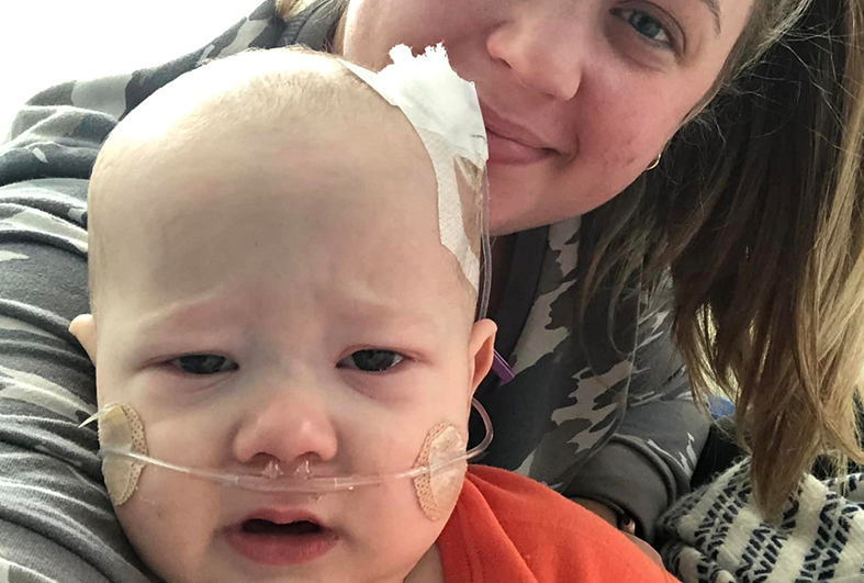 Mother posing for photo with baby wearing oxygen tube and experiencing RSV symptoms